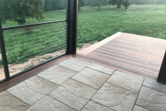 A patio area's tile flooring is outlined by the same wood that's been used for the adjoining sunburst-inspired deck that extends from the patio