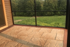 A patio area's earthy tile flooring is outlined by starburst-inspired wood that extends from a screened patio onto an open deck