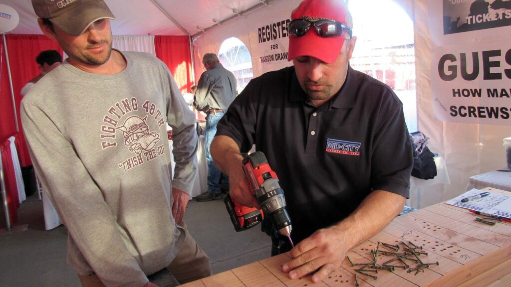 Two men drilling nails into a board