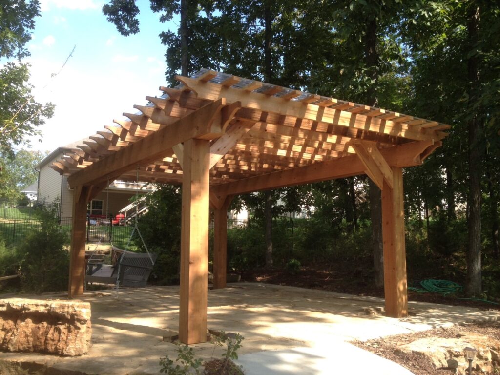 A custom pergola built from cedar stands strong, casting shadows from its lattice roof