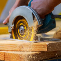 Close up of Carpenter's hand Using Circular Saw For Cutting Wooden Boards